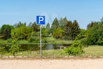 Parking sign in a park with lake and trees in background