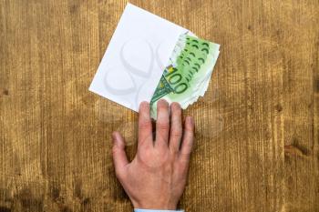 Hand takes an envelope full of 100 Euro banknotes . Shadow economy, illegal salary in an envelope without taxes.