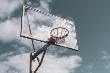 Basketball hoop against cloudy sky background. Filtered image.
