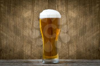 Glass of light lager beer on dark wooden background background