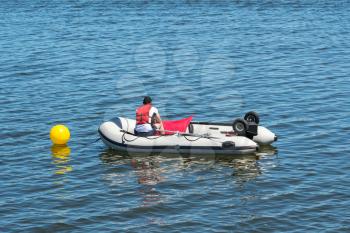 Lifeguard in an inflatable rescue boat patrolling in the lake. View from back.