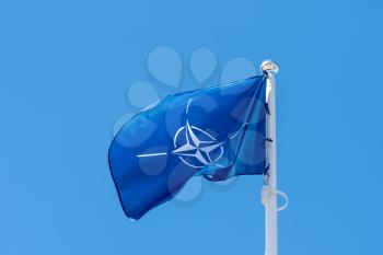 NATO flag waving in the wind against clear sky background