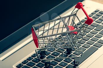  E-commerce. Shopping cart on laptop keyboard. Conceptual image.