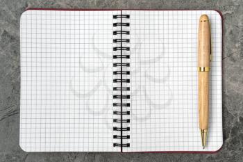 Blank notepad with a pen on stone background. Copy space.