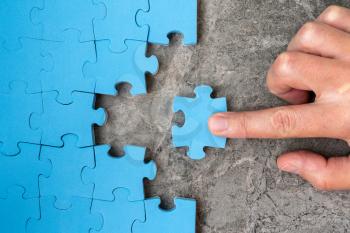 Concept of business.Hand holding piece of jigsaw puzzle and insert into the missing hole