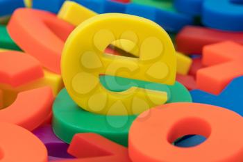 Yellow letter e on the pile of  colorful plastic letters and numbers