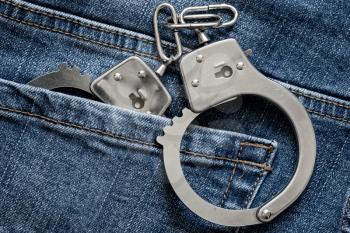 Handcuffs in blue jeans pocket.Close up view.