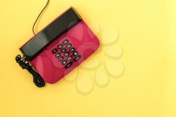   Old pink telephone on yellow background with copy-space