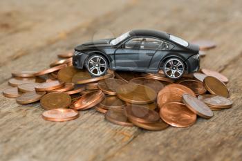 Saving for a new car. Toy car on a pile of coins