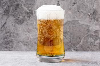 Glass of light beer on grey stone background