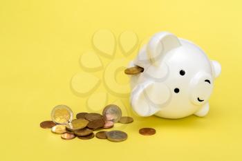 Money spilling out of the piggy bank on the yellow background