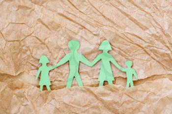 Family with two children, paper figures on a brown paper background