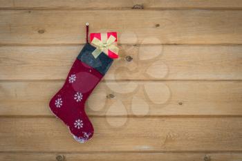 Christmas stocking full of gifts hanging on wooden wall