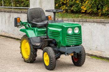 Green mini tractor standing on the street