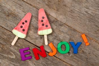 Fruity ice cream and word ENJOY on the wooden background 