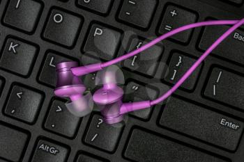 Purple audio earphones on the black keyboard. Home Audio Concept