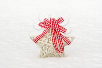 Christmas decoration star with a red bow in a fresh snow