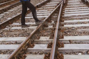 Man crosses the railway tracks. Concept of dangerous track crossing.