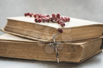 Catholic rosary lie on several ancient books. Close-up view.