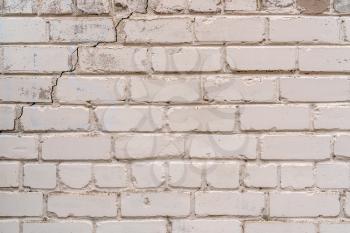 Old white brick wall background with a crack in a corner