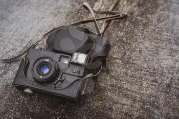 Retro black camera lying on the wooden background with a small amount of snow