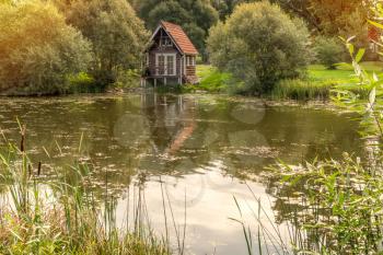 A small, wooden cabin near the edge of a small lake or pond