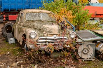Old rusty car on the junkyard waiting for recycling or destruction