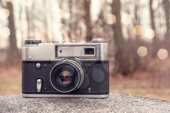 Old 35mm camera in the forest. Nature Photography Concept.