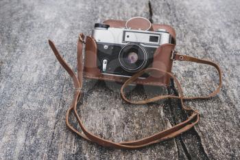 Retro 35mm camera lying on the wooden background