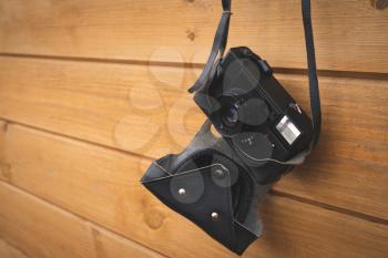 Old fashioned photo camera hanging on wood wall