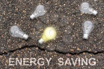 It's time for energy saving , one glowing  light bulb standing out from the other bulbs