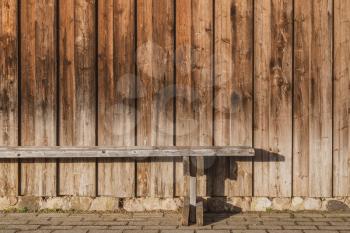 Empty long wooden bench against wooden wall