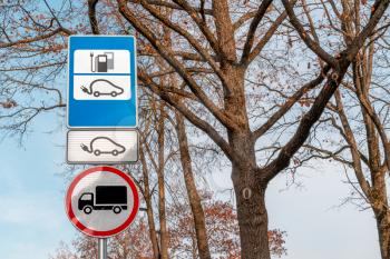 Electric car charging station road sign with trees background