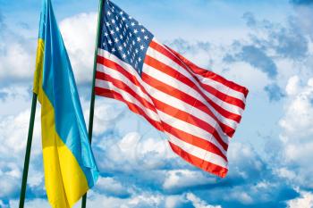 Flags of the USA and Ukraine against the background of the cloudy sky