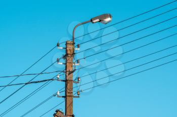 High voltage electric pole with lamp over a sky background