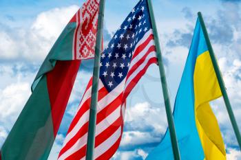 Ukraine, USA and Belarus flags. Flags in a one row on the cloudy sky background. 