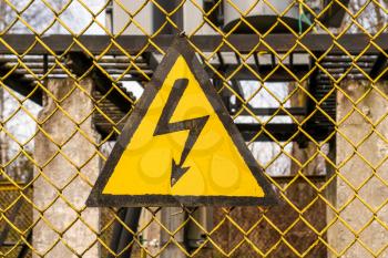 Yellow warning sign on fence of electricity substation
