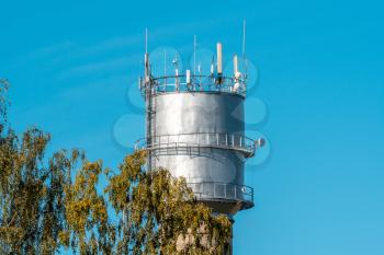 Water tower under blue sky with communication antennas. Telecommunications concept 