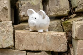 Piggy bank on the pile of old bricks. Saving money for house building or renovation