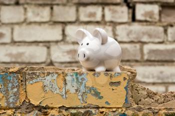 Piggy bank on the wall of dismantled building. Saving money for house building or renovation