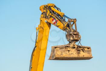 Excavator arm and backhoe on the clear sky background