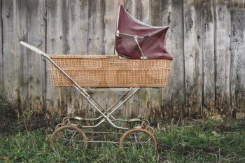 Retro style stroller baby carriage outdoors on old wall background