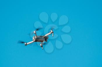 Drone with camera flying over blue sky background 
