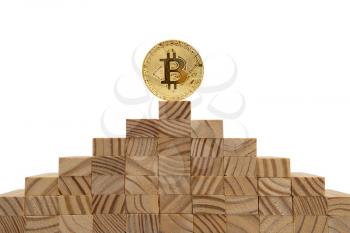 Bitcoin standing on top of a pyramid of wooden cubes. Copy space.