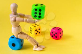 Wooden mannequin with game dice on the yellow background