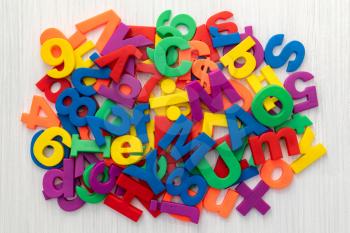 A pile of coloured magnetic letters and numbers over a wooden table