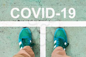 Stay safe by stay home. Man stops at the line with text COVID-19.