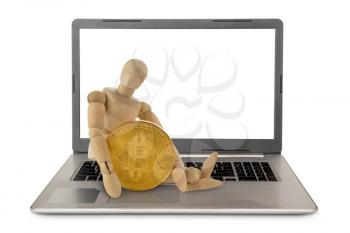 Wooden doll sitting on the laptop and tightly holding Bitcoin. Cryptocurrency concept.
