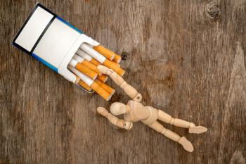 Wooden dummy takes a cigarette. Bad habit concept.