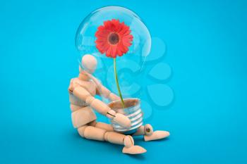 Wooden man holds a  light bulb with red flower inside. Concept of green energy
